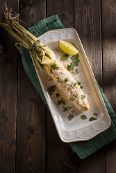 Elote recipe or mexican street corn recipe in a square white porcelain dish with lime wedge on wooden table.