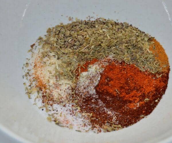 Creole seasoning being mixed in a white mixing bowl. 